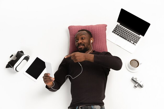 Young man using phone surrounded by gadgets