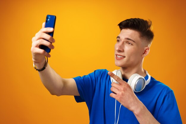 黄色の背景にスマートフォンを使用して若い男