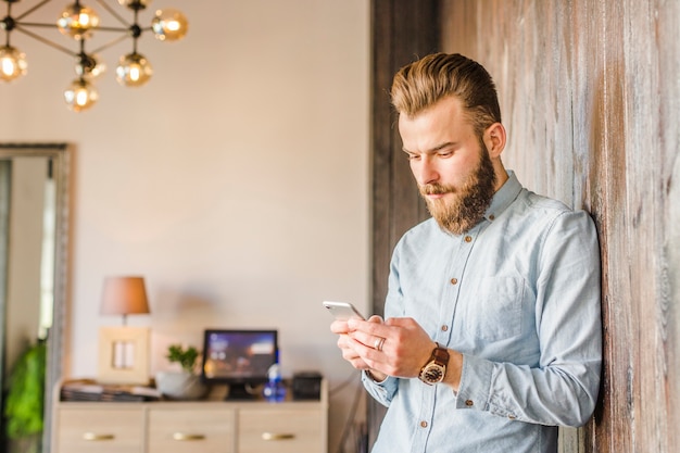 Free photo young man using smartphone at home