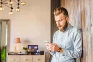 Free photo young man using smartphone at home