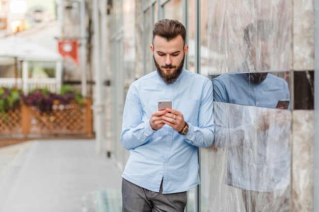 Giovane che per mezzo dello smartphone all'aperto