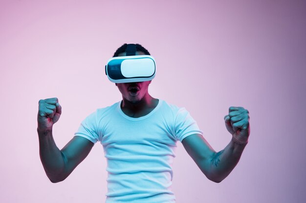 Young man using VR glasses in neon light