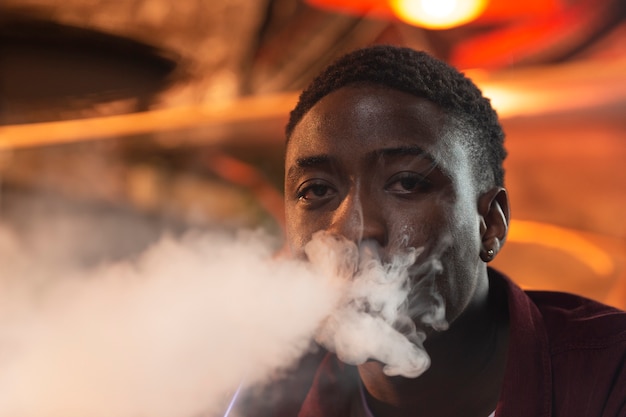 Young man vaping from a hookah in a bar