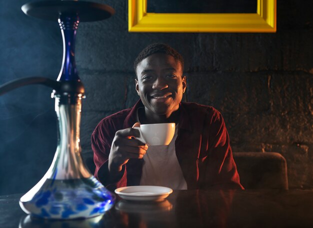 Young man vaping from a hookah in a bar