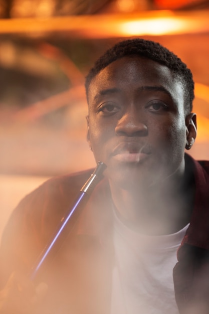 Young man vaping from a hookah in a bar