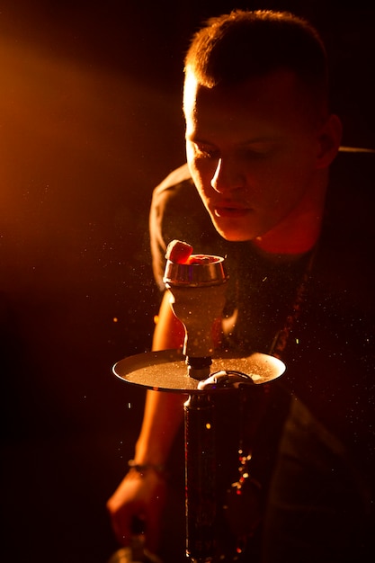 Young man vaping from a hookah in a bar