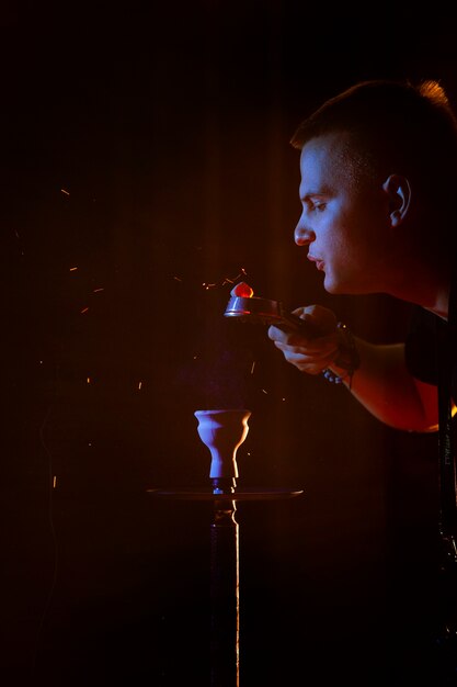 Young man vaping from a hookah in a bar