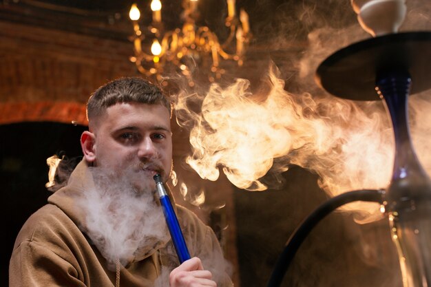 Young man vaping from a hookah in a bar