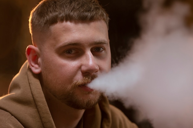 Free photo young man vaping from a hookah in a bar
