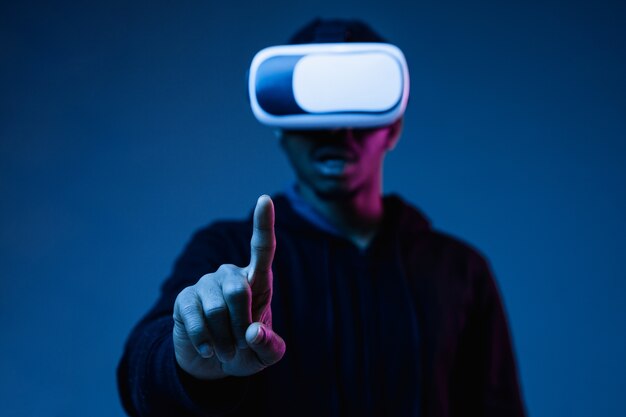 Young man in VR-glasses in neon light on blue