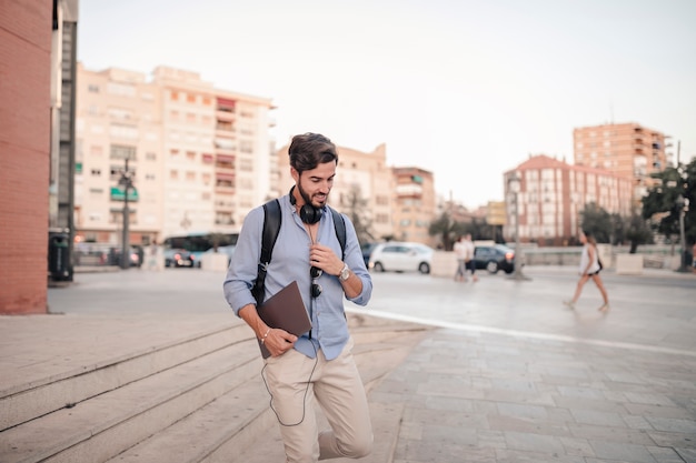 Young man walking down staircase with laptop