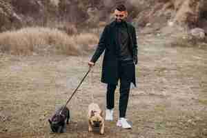 Free photo young man walking his french bulldog in park