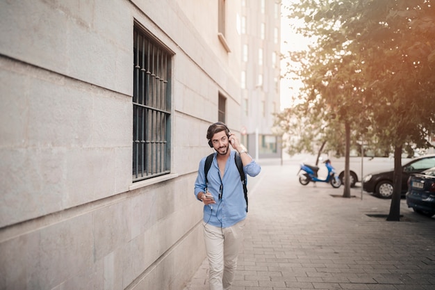 Young man walking on pavement listening to music