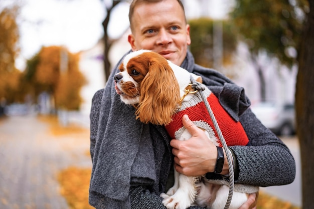 Young man walking with a dog in the autumn park