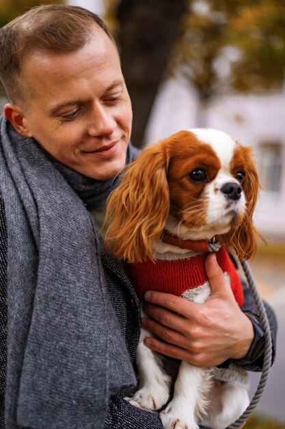 秋の公園で犬と一緒に歩いている若い男