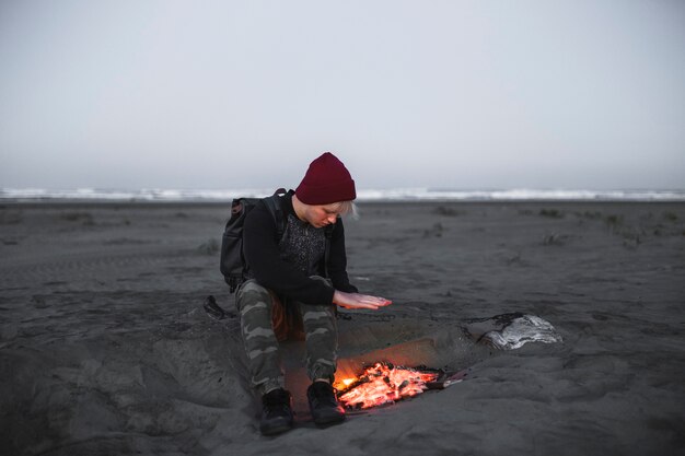 Young man warming near fire