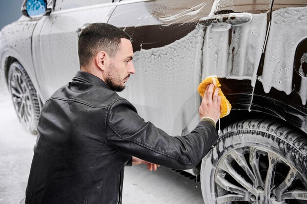 Young man washing car on carwash station outdoor