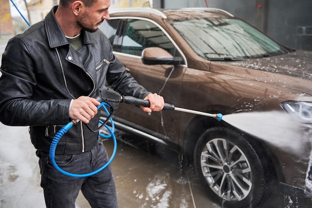 Free photo young man washing car on carwash station outdoor