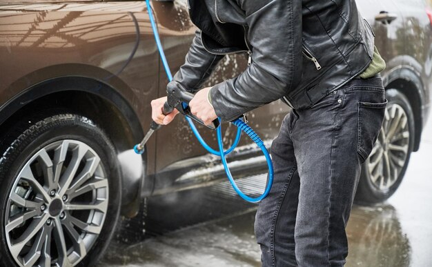 Young man washing car on carwash station outdoor