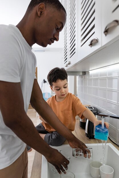 Young man washing dishes with his son