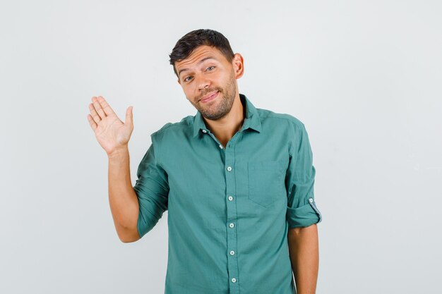 Young man waving hand for greeting in shirt and looking cheerful