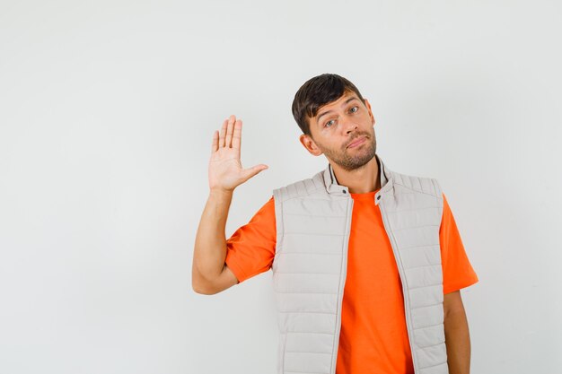 Young man waving hand to say goodbye in t-shirt, jacket