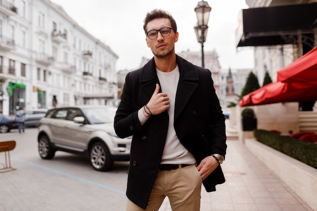 Young man wearing  autumn clothes walking on the street. Stylish guy with modern hairstyle in urban street.
