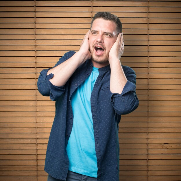 Young man wearing a blue outfit. Covering his ears.