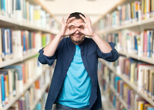 Young man wearing a blue outfit. Doing glasses gesture.