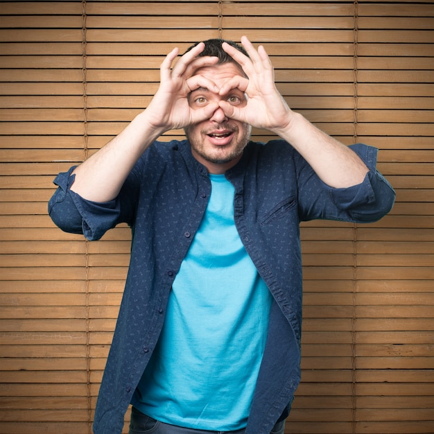 Young man wearing a blue outfit. Doing glasses gesture.