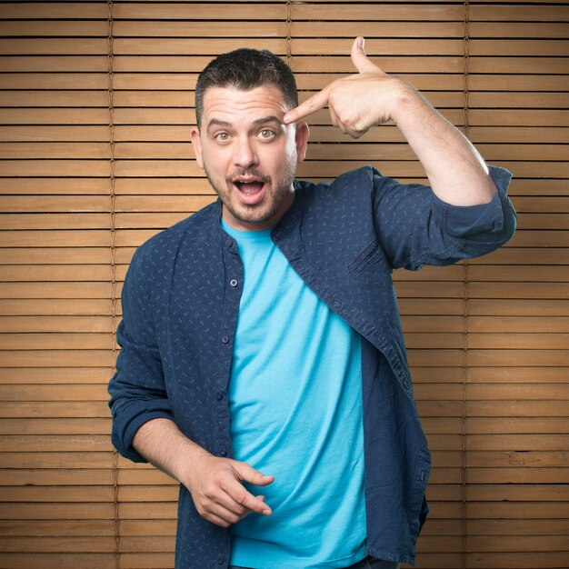 Young man wearing a blue outfit. Doing gun gesture.