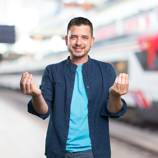 Young man wearing a blue outfit. Doing money gesture.