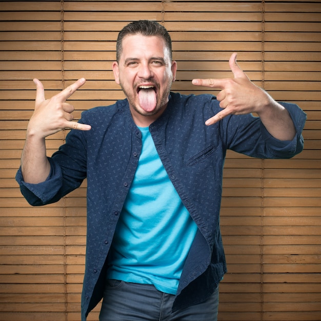 Free photo young man wearing a blue outfit. doing rock sign.