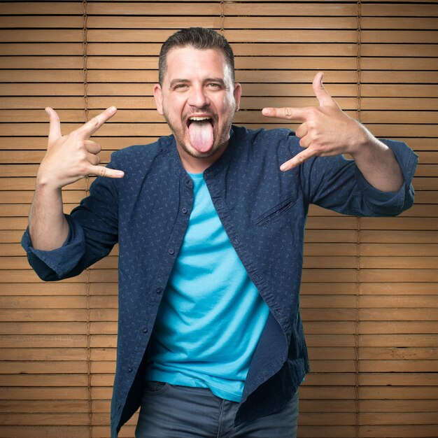 Young man wearing a blue outfit. Doing rock sign.