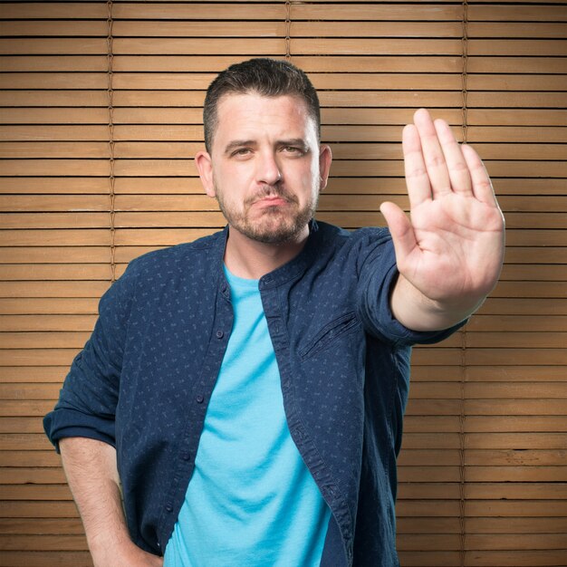 Young man wearing a blue outfit. Doing stop gesture.