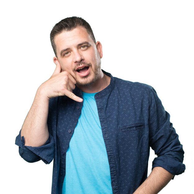 Young man wearing a blue outfit. Doing telephone gesture.