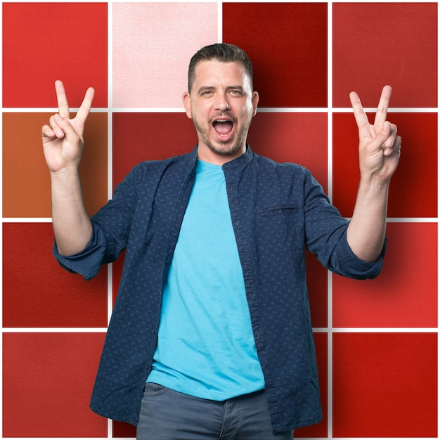 Young man wearing a blue outfit. Doing victory gesture.