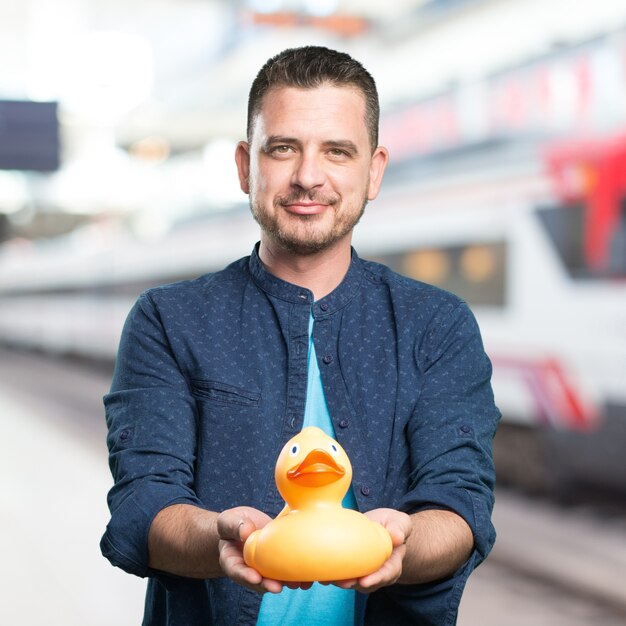 Young man wearing a blue outfit. Holding a toy duck. Offering.
