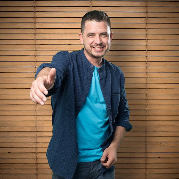 Young man wearing a blue outfit. Offering his hand.