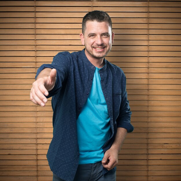 Young man wearing a blue outfit. Offering his hand.