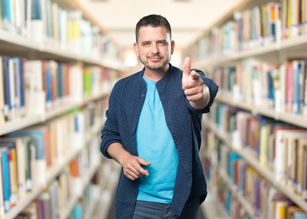 Young man wearing a blue outfit. Pointing with gun gesture.