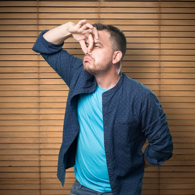 Young man wearing a blue outfit.Stinky gesture.