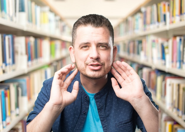 Young man wearing a blue outfit. Touching his ears.