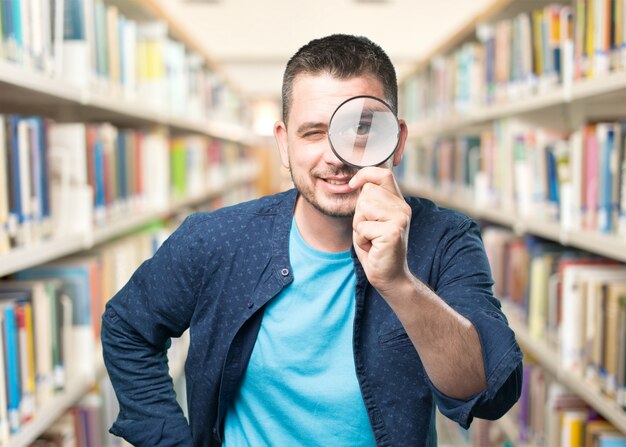 Young man wearing a blue outfit. Using a magnifying glass. Smili