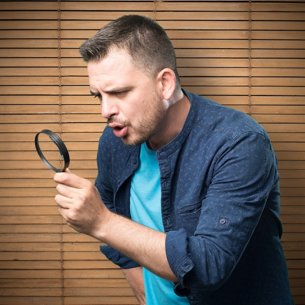 Free photo young man wearing a blue outfit. using a magnifying glass.