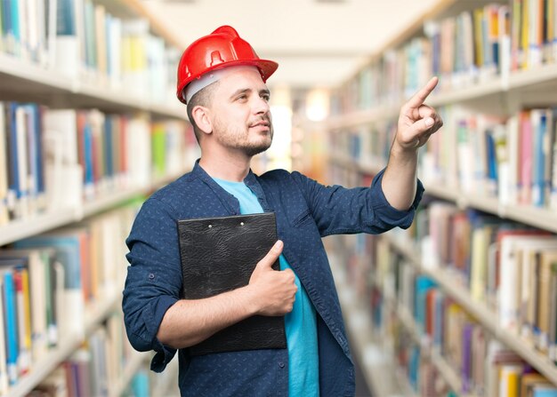 Young man wearing a blue outfit. Wearing red helmet. Pointing to