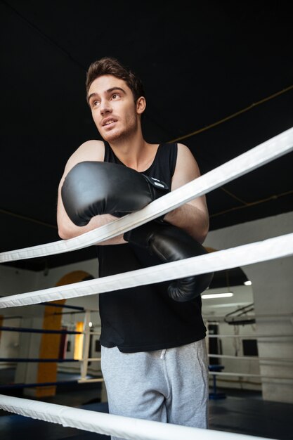 Young man wearing boxing gloves looking away