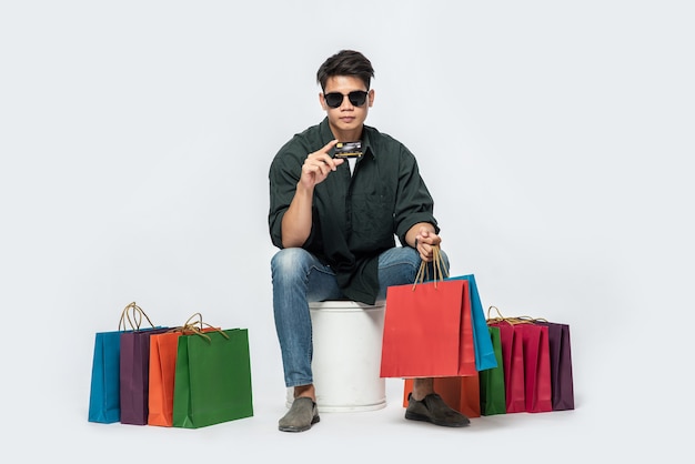 A young man wearing a dark shirt and jeans, carried several bags to go shopping with a credit card