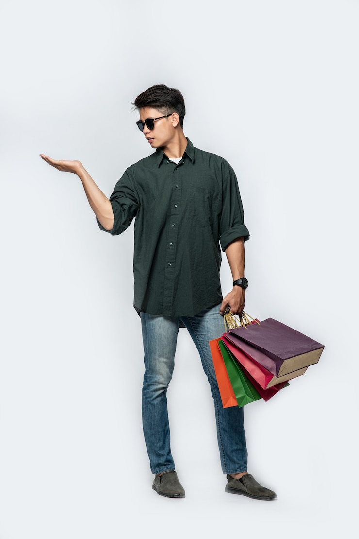 Free Photo a young man wearing a dark shirt and jeans carries many bags to go shopping