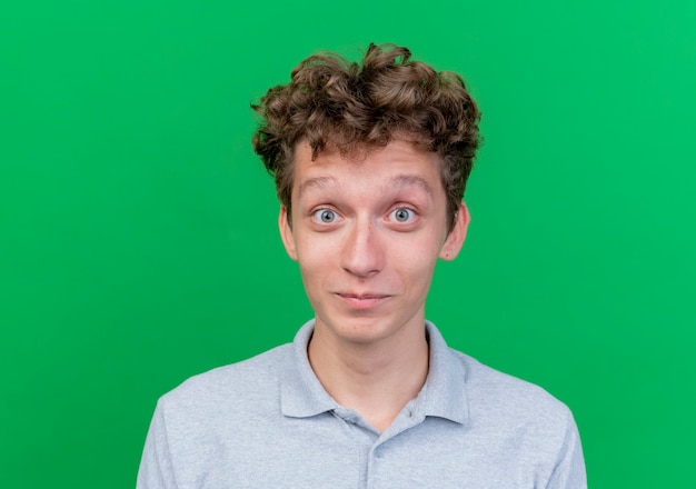 Free photo young man wearing grey polo shirt with wide open eyes happy and positive over green